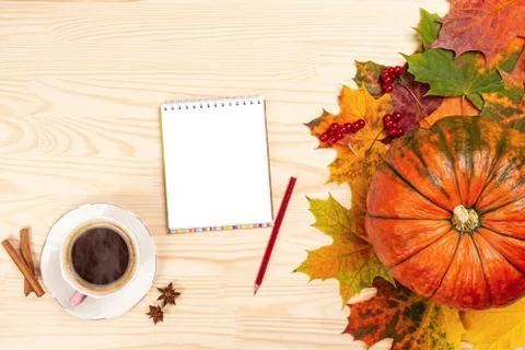 Autumn composition. notebook with pen, hot coffee, pumpkin, leaves on white w Stock Photos