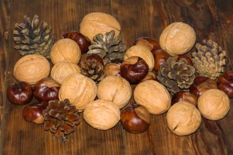 Autumn composition. Pine cones, walnuts, chestnuts on wooden Dark rustic Stock Photos