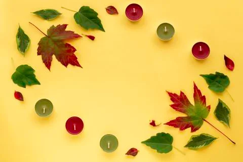 Autumn flat lay. Frame from red green leaves and candles on yellow paper back Stock-Fotos