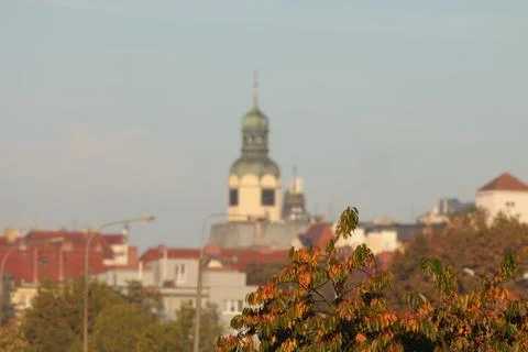 Autumn foliage frames a softly focused historic church tower above a Europe.. 库存照片