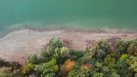 Autumn forest next to river shore top down drone shot. Teal water and fall color Stock Footage 163540165