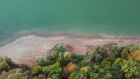 Autumn forest next to river shore top down drone shot. Teal water and fall color Stock Footage 163545459