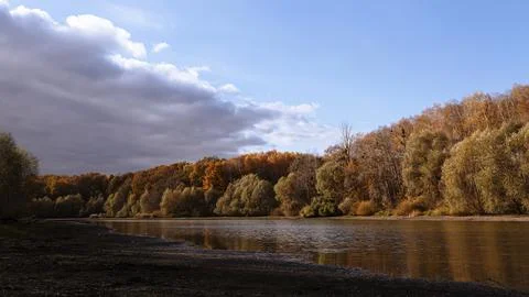 Autumn forest over river with dramatic clouds, background Foto stock