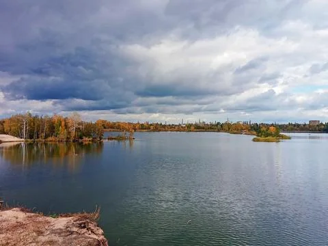 Autumn lake landscape with dramatic cloudy sky and calm water Stock Photos