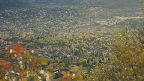 Autumn leaves frame a sprawling small village or town in France's Provence Видео 339098217