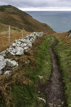 Autumn or fall path with remains of dry stone wall, and sea in distance. Stock Photos