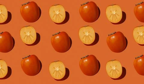 Autumn pattern is made with half a persimmon on a orange background. Stock Photos