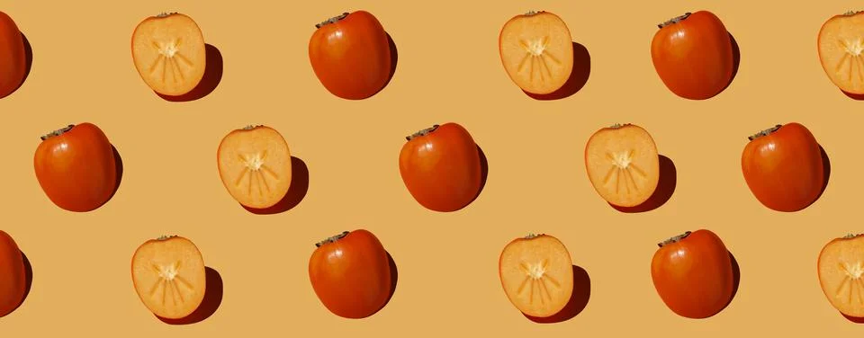 Autumn pattern is made with half a persimmon on a orange background. Stock Photos
