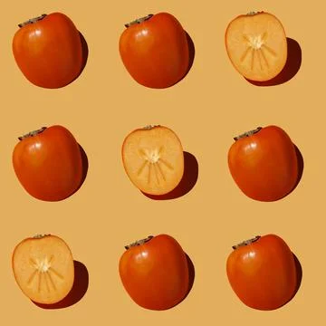 Autumn pattern is made with half a persimmon on a orange background. Stock Photos