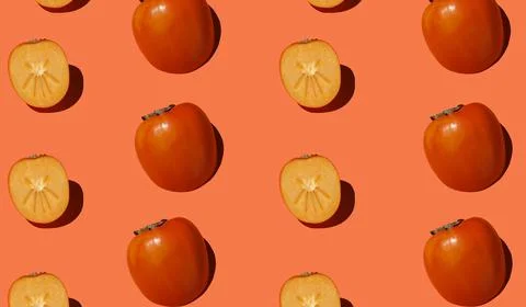 Autumn pattern is made with half a persimmon on a orange background. Stock Photos