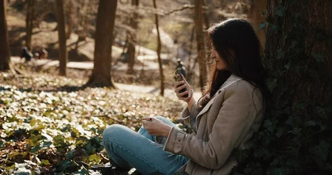 Autumn / spring vibes. Charming young woman reads something in her smartphone Stock Footage 106442684
