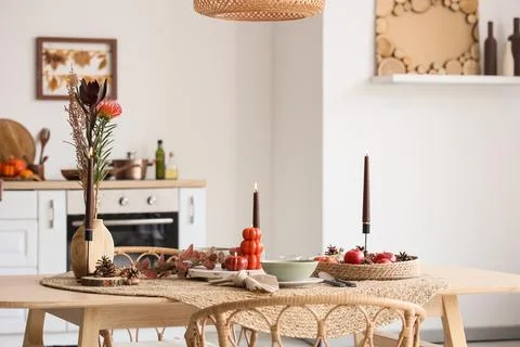 Autumn table setting with burning candles and flowers in interior of kitchen Stock Photos