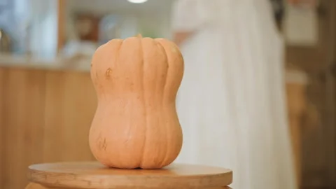 Autumn themed kitchen setting featuring pumpkin and baker in softly lit scene Stock Footage 346392984