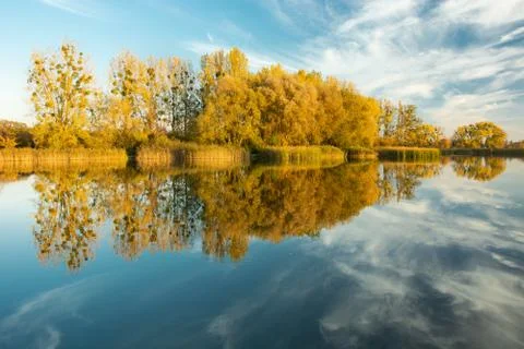 Autumn trees and clouds reflected in the lake water Stock-Fotos
