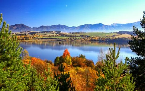 Autumn trees and mirror reflection of mountains in lake Stock Photos