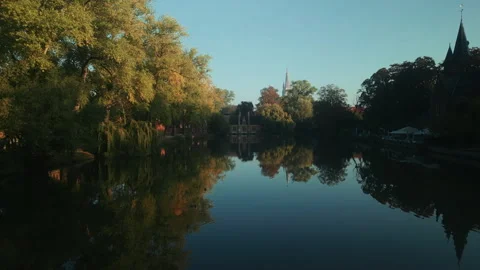 Autumn trees and waterfowl reflected in calm Bruges lake at dawn Vídeo Stock 346674710