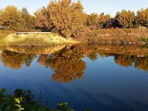 Autumn trees reflected in calm river water Stock Photos
