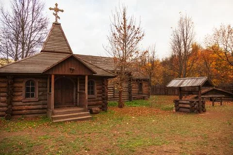 Autumn village landscape. Wooden houses and a church stand against the backgr Stock Photos