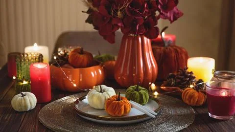 Autumnal table setting with decorative pumpkins, candles and string lights Stock Photos