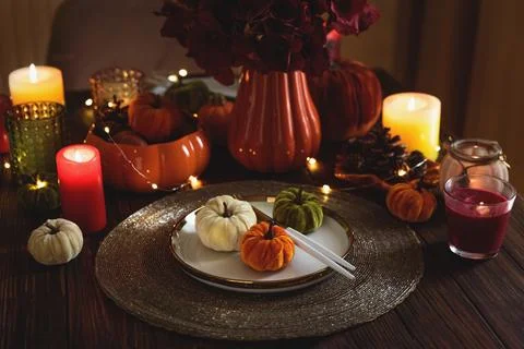 Autumnal table setting with decorative pumpkins, candles and string lights Stock Photos