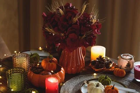 Autumnal table setting with decorative pumpkins, candles and string lights Stock Photos