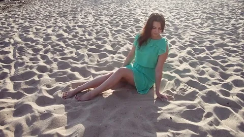 Average plan. Beautiful girl playing with sand on the beach. Stock Footage 77211514