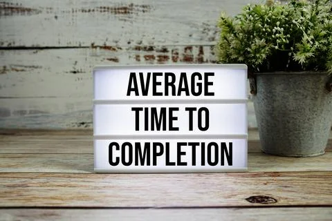 Average Time to Completion text with alarm clock on wooden background Stock Photos
