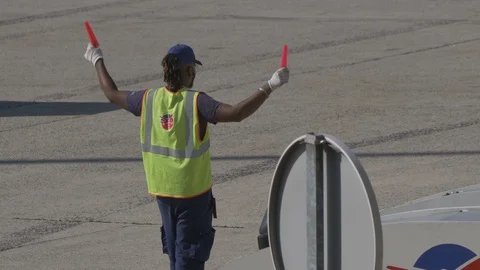 Aviation marshall signals to approaching plane with marshalling wand Stock Footage 119826371