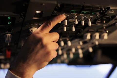 Aviation pilot using control panel in cockpit to fly airborne aircraft Stock Photos