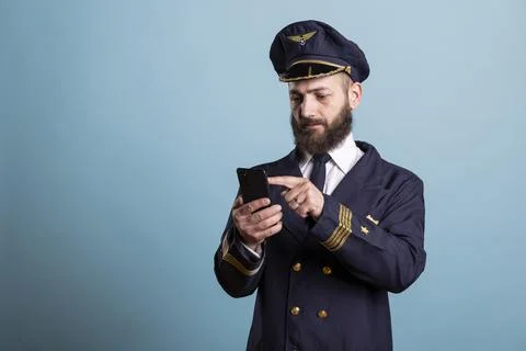 Aviator typing on smartphone, studio backdrop Stock Photos