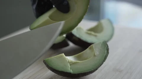 Avocado being cut into 4 pieces by female hands in black gloves. Close up Stock Footage 243283458