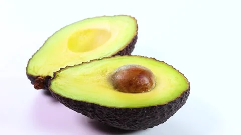 Avocado cut in half on white background, rotating Stock Footage 318377492