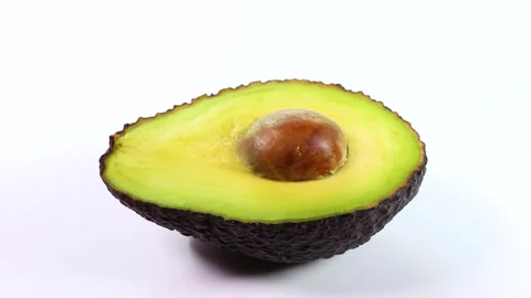 Avocado cut in half on white background, rotating Video stock 318377493