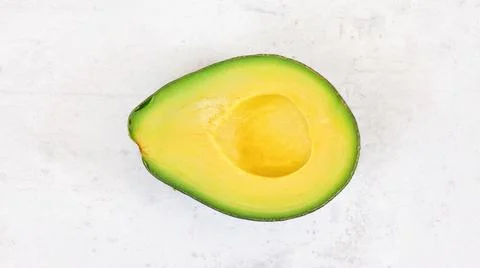 Avocado half, with bright yellow pulp on white stone board, photo from above Foto stock
