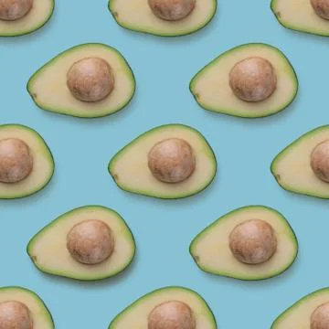 Avocado halves pattern on blue background. Tropic fruits, organic food Stock Photos