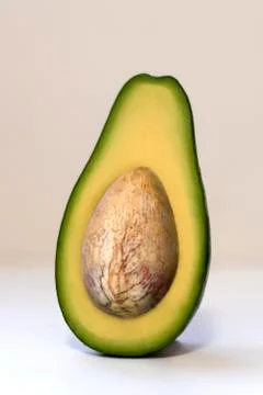 Avocado halves with a stone stands vertically. Stock Photos