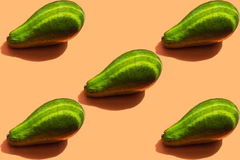 Avocado pattern with shadow on an orange background. The avocado has two stri Stock Photos
