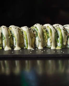 Avocado rolls sit elegantly on a dark slate 库存照片
