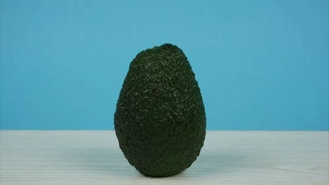 Avocado rotates on table and blue background Video stock 125952832