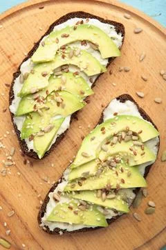 Avocado sandwich on dark rye bread made with fresh sliced avocados on brown b Stock Photos