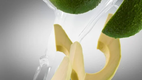 Avocado with Slices and Splash Falling on Dark Grey Background Stock Footage 122703959
