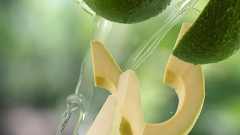 Avocado with Slices and Splash Falling on Garden Background Video stock 122704033