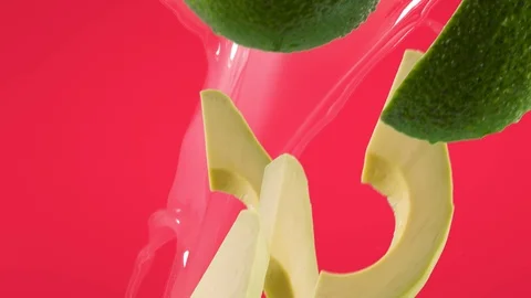 Avocado with Slices and Splash Falling on Fuchsia Background Vídeo Stock 122704326