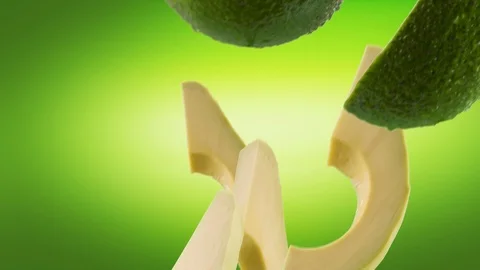 Avocado with Slices Falling on Green Background Stock Footage 122704486