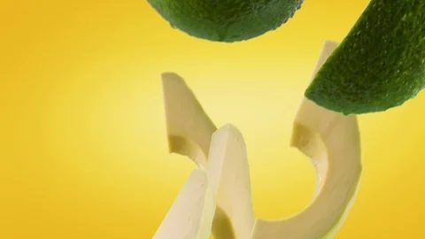 Avocado with Slices Falling on Yellow Background Stock Footage 122703913