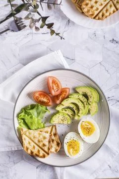 Avocado, soft boiled egg, tomatoes, lettuce and toast on a plate. Healthy food. Stock Photos