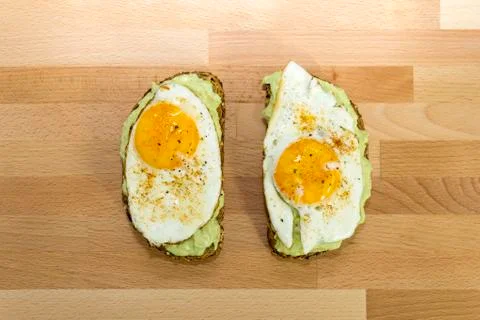Avocado toast and fried egg on wooden background for breakfast Stock Photos
