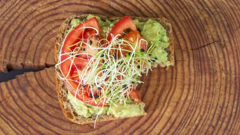 Avocado toast bite by bite looped animation. Dark natural wooden background Stock Footage 128923296