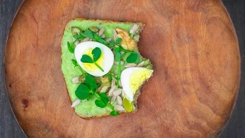 Avocado toast eating bite by bite. Toast with quail eggs, sunflower seeds Stock Footage 129244885