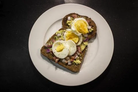 Avocado toast with egg, bacon bits and onion Stock Photos